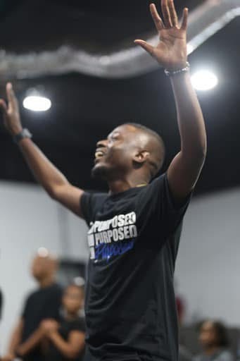 Man in a Purposed shirt worshipping with hands raised